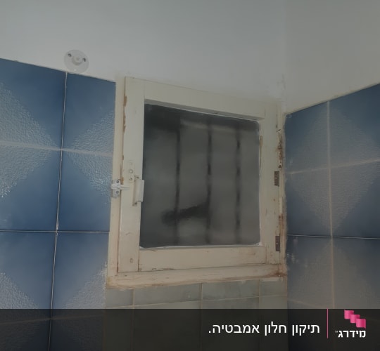 חלון קטן עם תריסים ישנים בחדר אמבטיה